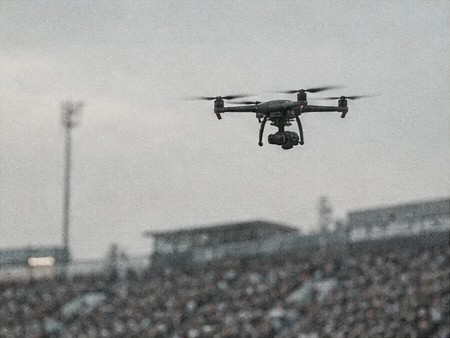 Quadcopter camera drone hovering above stadium stands